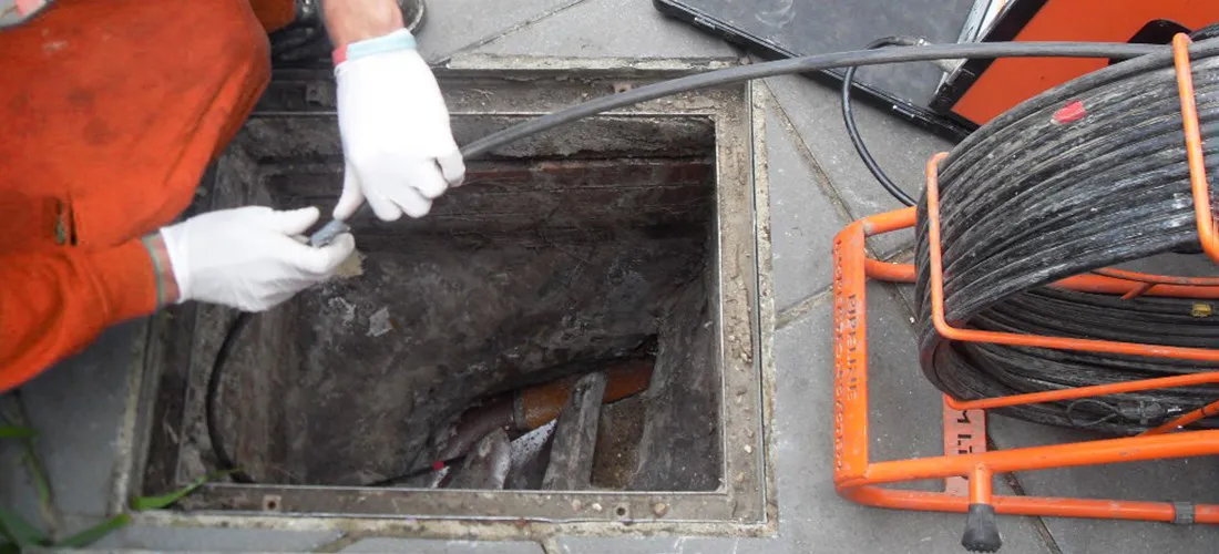 Drain technician performing a CCTV camera inspection of a manhole or drain