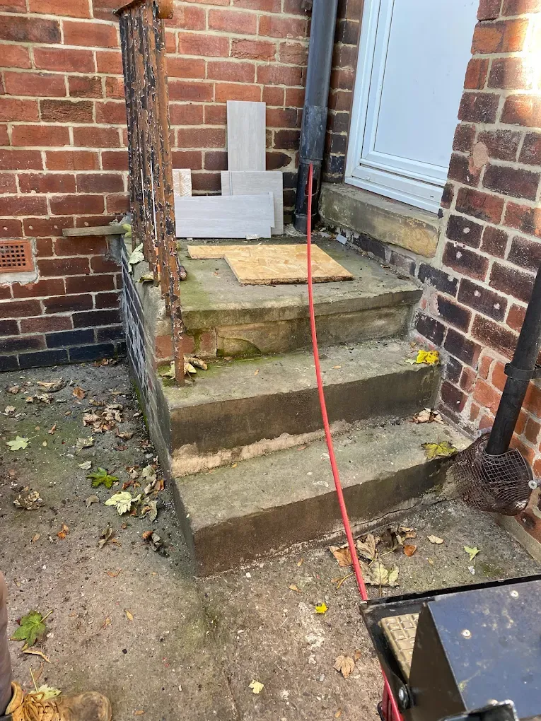 Outdoor drainage work near property steps and entrance