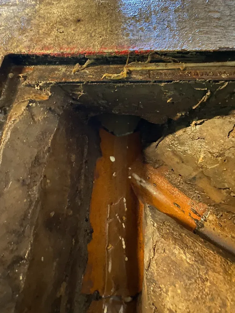 Inside view of a drain channel with standing water and sediment.