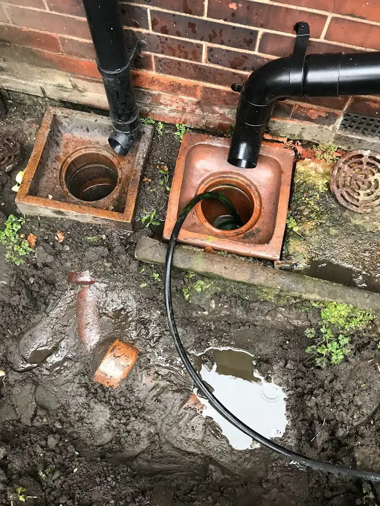 External drain gullies next to a house foundation with a pipe inserted